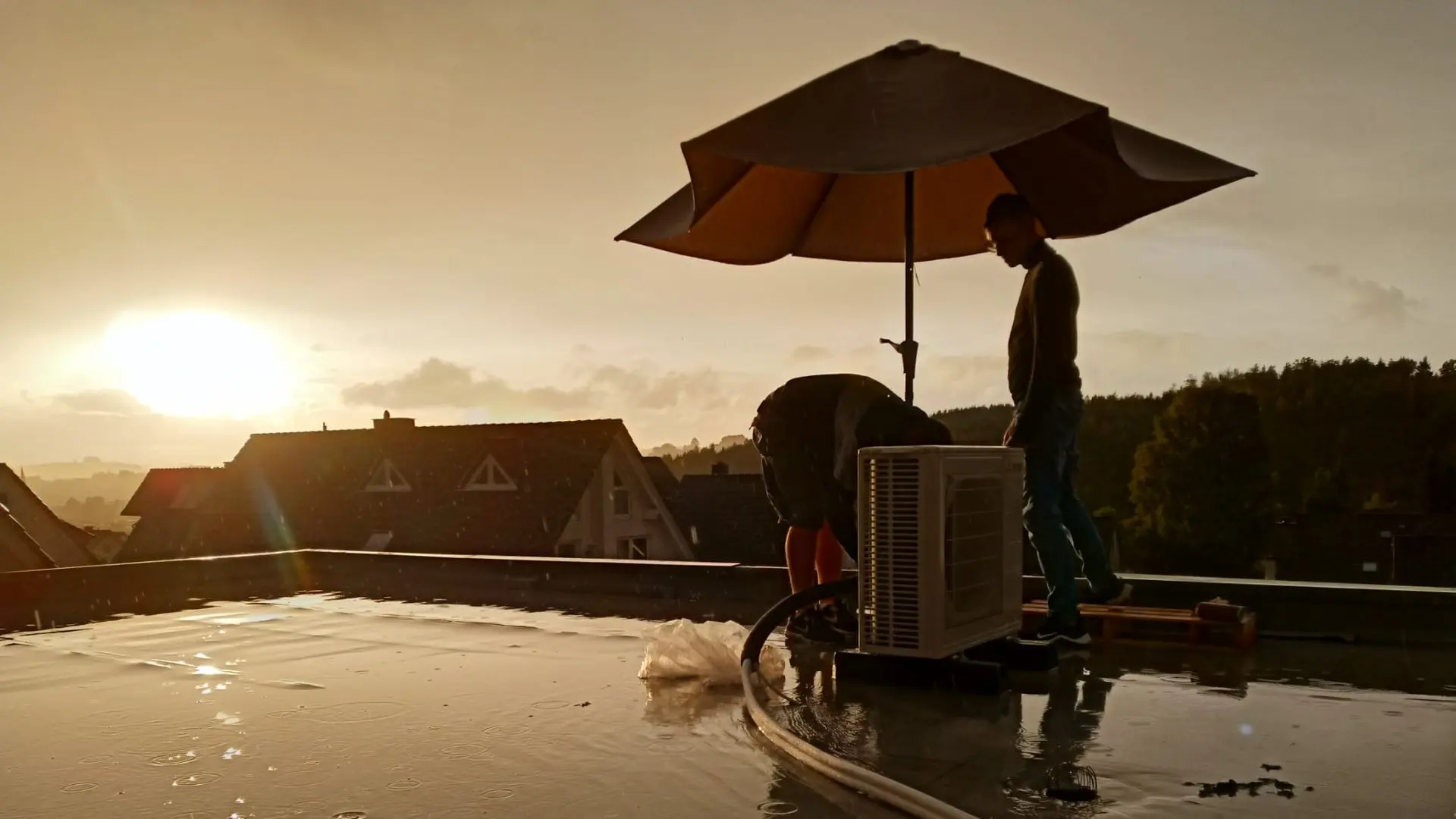 Installation einer Klimaanlage in NRW auf Flachdach bei Regen und Sonnenuntergang durch HKK Hemmerich