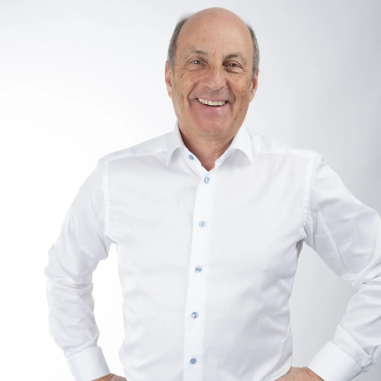 Geschäftsführer Stefan Ott von Confinity Solutions in weißem Hemd, lächelnd vor neutralem Hintergrund.