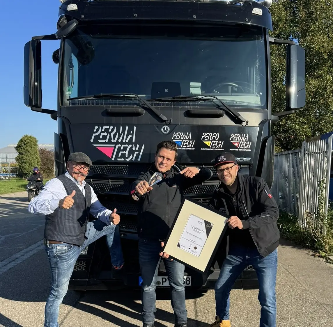Team der PERMATECH INDUSTRIE SERVICE GmbH vor schwarzem Firmen-LKW mit HIPE AWARD