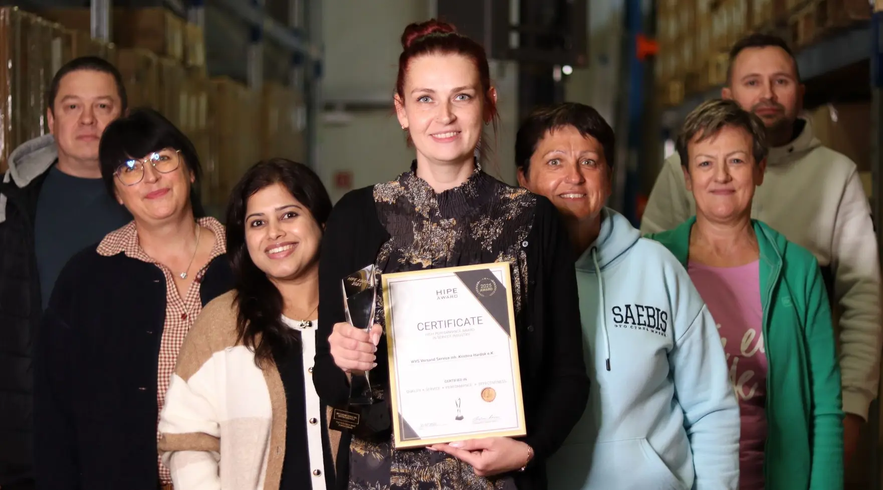 WVS Versand Service als HIPE AWARD Preisträger – Teamfoto mit Geschäftsführerin Kristina Hardok Team von WVS Versand Service mit Geschäftsführerin Kristina Hardok und HIPE AWARD im Lager